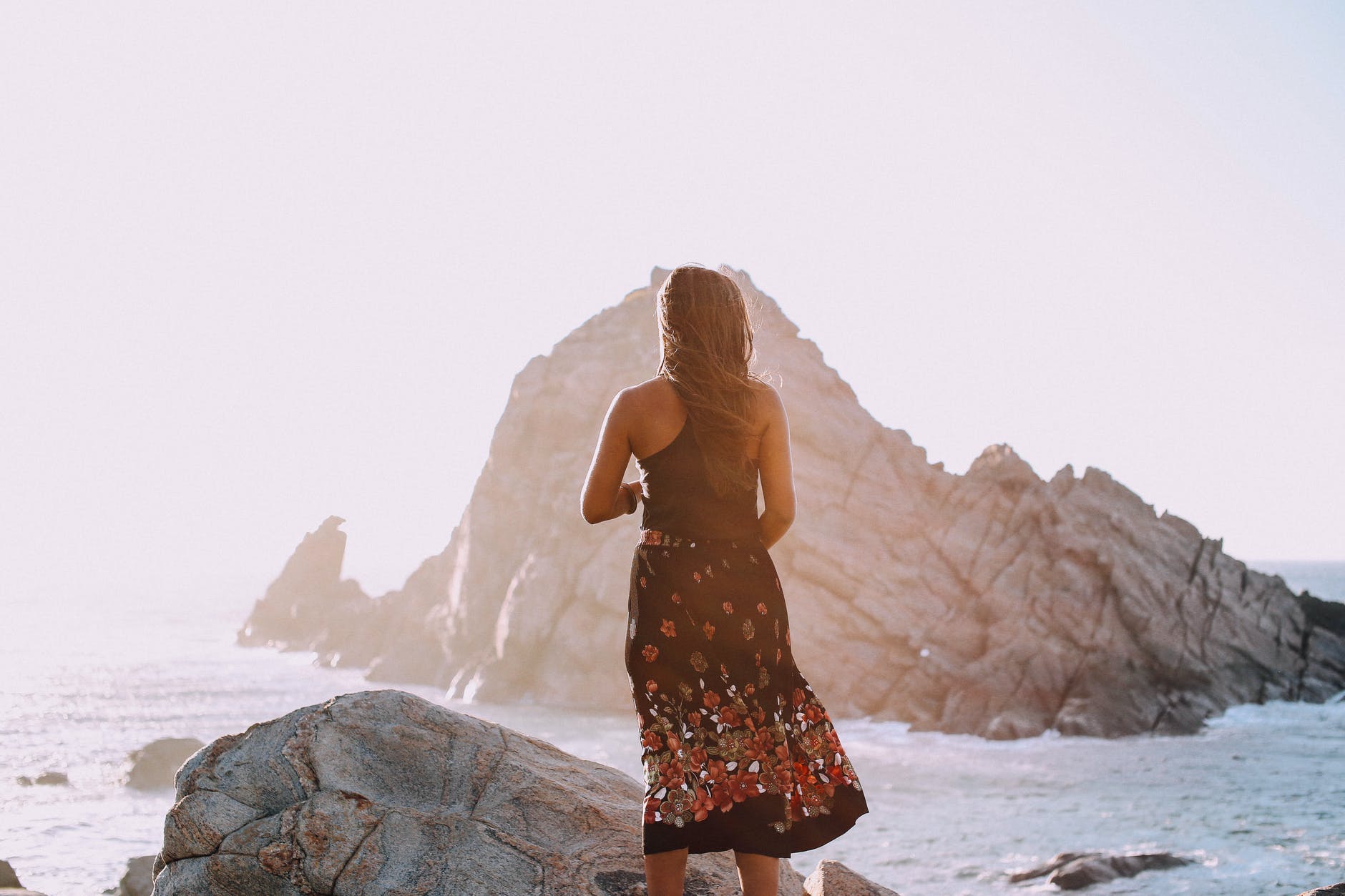 unrecognizable stylish woman standing on rocky seashore